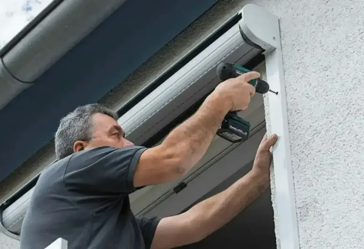 Technicien fixant le coffre d'un volet roulant à la visseuse